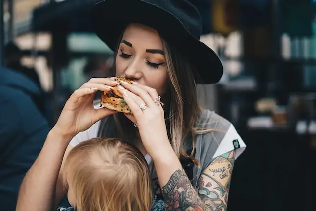 문신을 한 여자가 햄버거를 먹고 있습니다.